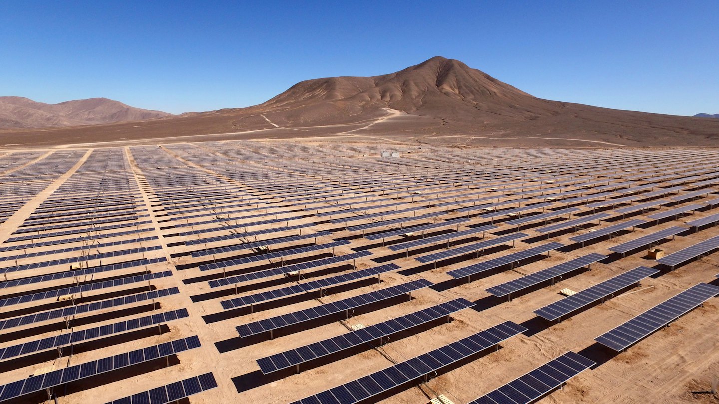 Rows of solar panels in a desert landscape.