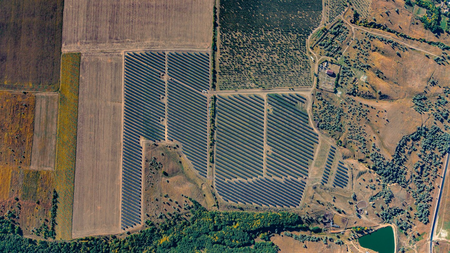 Solar panels installed across a rural landscape of farm fields.